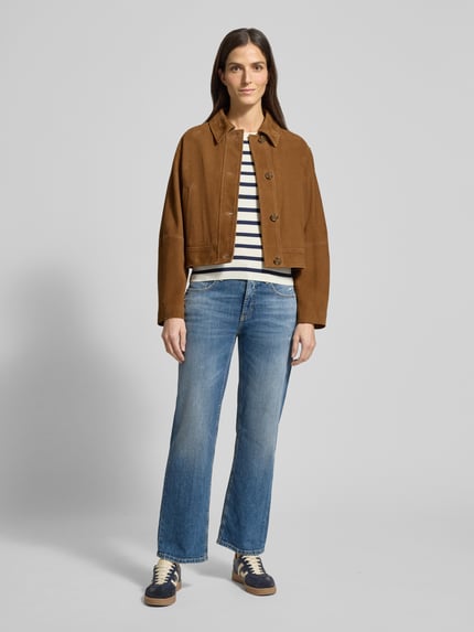 Frauenmodel trägt Flared Jeans mit 5-Pocket-Design Modell 'GINI' von Cambio aus Baumwoll-Elasthan-Mix, mittleres Blau, Ganzkörperansicht von vorne.