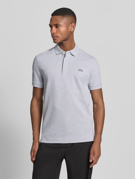 Männermodel trägt Regular Fit Poloshirt aus Baumwoll-Mix von Lacoste, Optik: Unifarben, Logo-Stitching, Piquéstruktur, Ganzkörperansicht von vorne.
