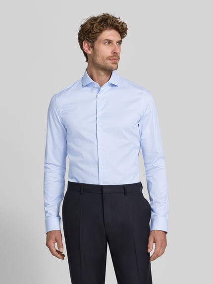 Männermodel trägt Slim Fit Businesshemd mit extra langem Arm von Jake*s in Hellblau mit feiner Struktur, Ganzkörperansicht von vorne.