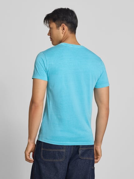 Männermodel trägt T-Shirt mit Rundhalsausschnitt und Label-Stitching von Superdry in Hellblau, reine Baumwolle, Rückenlänge 66 cm, Ganzkörperansicht Rückansicht.