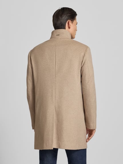 Männermodel trägt Mantel mit hohem Stehkragen Modell 'MARAN' von JOOP!, unifarben beige, Longline, Ganzkörperansicht Rückansicht.