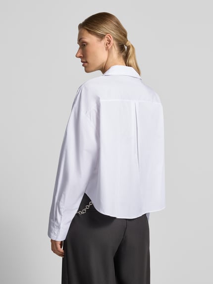 Frauenmodel trägt Relaxed Fit Hemdbluse aus Viskose-Mix Modell 'Anna' von MANGO, weiß, Hemdblusenkragen, verlängerte Rückseite, Ganzkörperansicht Rückansicht.