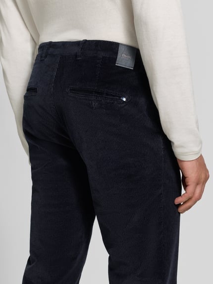 Männermodel trägt dunkelblaue Modern Fit Cordhose aus Baumwoll-Mix Modell 'Fabio' von Brax, feine Rippenstruktur, Herren Schmale Hose, Ganzkörperansicht Rückansicht.