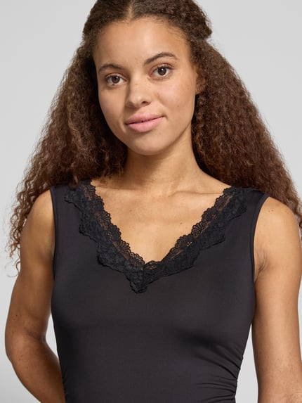 Frauenmodel trägt Wäschebody mit Spitzeneinsatz am V-Ausschnitt von ONLY, unifarbenes Jersey, breite Träger, Nahaufnahme Oberkörper.