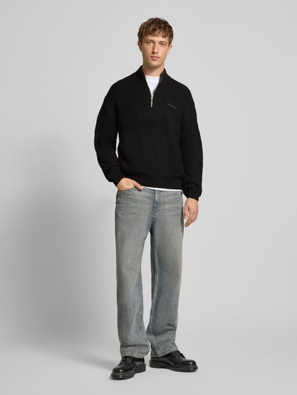 Männermodel trägt Regular Fit Troyer mit Reißverschluss von REVIEW in Schwarz mit Label-Stitching, Ganzkörperansicht von vorne.