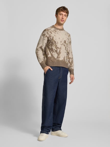 Männermodel trägt Pullover mit gerippten Abschlüssen von ONLY in mehrfarbiger Strickoptik mit abstraktem Allover-Muster, Ganzkörperansicht von vorne.