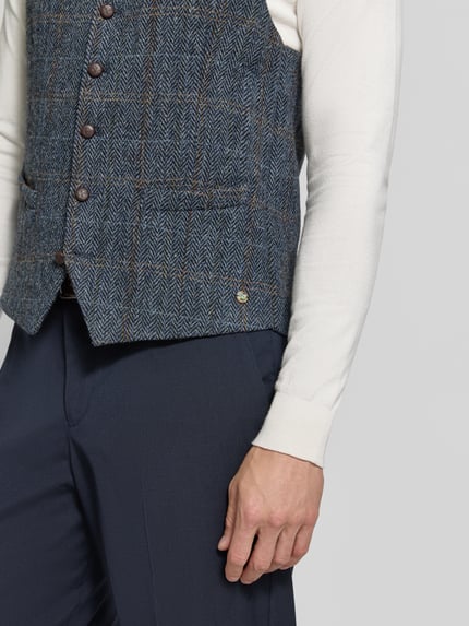Männermodel trägt Weste aus Schurwolle mit Brustleistentasche Modell 'Warner' von Carl Gross, strukturierte Wolloptik, Nahaufnahme Oberkörper. Herren Weste von Carl Gross, Reine Schurwolle, Regular Fit, Reverskragen, Knopfleiste, Brustleistentasche, seitliche Leistentaschen, Rückenlänge 64 cm, Schulterbreite 39 cm, Brustweite 52 cm.