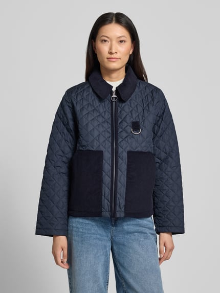 Kobiece model prezentuje granatową kurtkę pikowaną Regular Fit Steppjacke mit aufgesetzten Seitentaschen Modell 'AYLESBY' od Barbour, damska kurtka pikowana, prosty fason, prostokątne kieszenie, tekstura pikowania, Ganzkörperansicht von vorne.