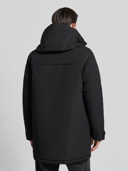 Männermodel trägt Parka mit Kapuze und Pattentaschen Modell 'AIDEN' von Didriksons, schwarze glatte Oberfläche, Ganzkörperansicht Rückansicht. Regular Fit, verdeckter Reißverschluss, Rückenlänge 95 cm, Schulterbreite 47 cm, Brustweite 55 cm, Ärmellänge 68 cm.