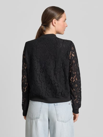 Männermodel trägt Regular Fit Blouson aus Baumwoll-Mix Modell 'HONEY' von Vero Moda, czarny, ażurowy, wzór kwiatowy, college-kragen, rękaw długi, zakończenia ściągaczowe, widoczna faktura haftu, Ganzkörperansicht Rückansicht.