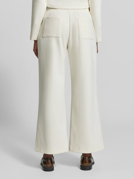 Frauenmodel trägt Cordhose mit elastischem Bund von Christian Berg Woman, Farbe Creme, weites Bein, Gesäßtaschen, Material-Mix, Ganzkörperansicht Rückansicht.