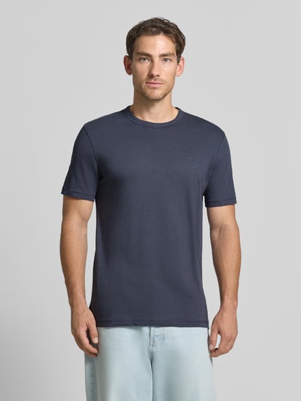 Męski model nosi Regular Fit T-Shirt aus Baumwoll-Mix Modell 'Tegood' von BOSS Orange, ciemnoniebieski odcień, gładka tekstura, Ganzkörperansicht von vorne.