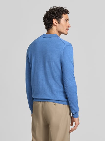 Mężczyzna nosi Regular Fit Pullover aus reiner Wolle von Polo Ralph Lauren w kolorze niebieskim, neutralne spodnie, jednolita faktura, Ganzkörperansicht Rückansicht.