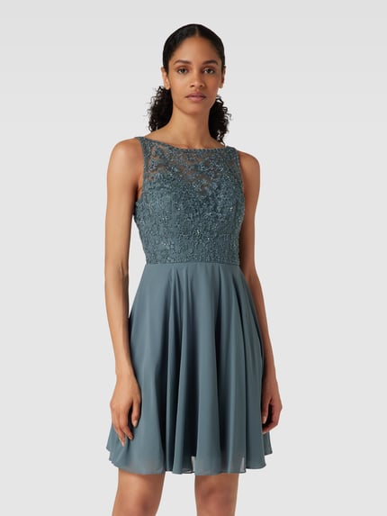 Frauenmodel trägt Regular fit Minikleid mit floralem Spitzenbesatz von Laona in semitransparenter Optik mit Ziersteinbesatz, Nahaufnahme Oberkörper.