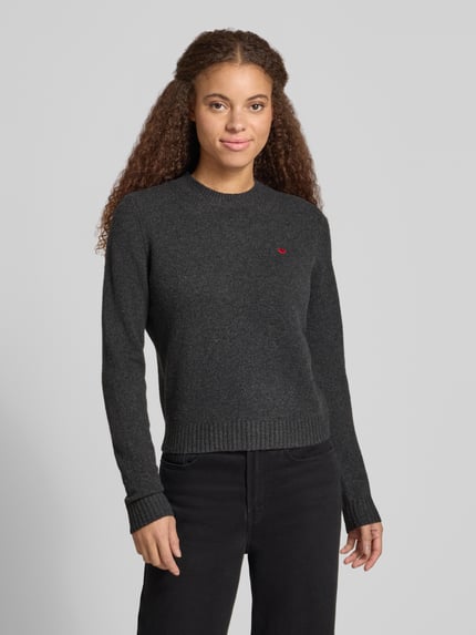 Kobiece model nosi Slim Fit Strickpullover aus elastischem Material-Mix od REVIEW, elastyczna mieszanka materiałów, krój slim fit, Wyhaftowany motyw, prążkowane wykończenia, długość tyłu w rozmiarze S: 51 cm, długość rękawów w rozmiarze S: 61 cm, ciemny szary kolor, prosta faktura, cała sylwetka z przodu.