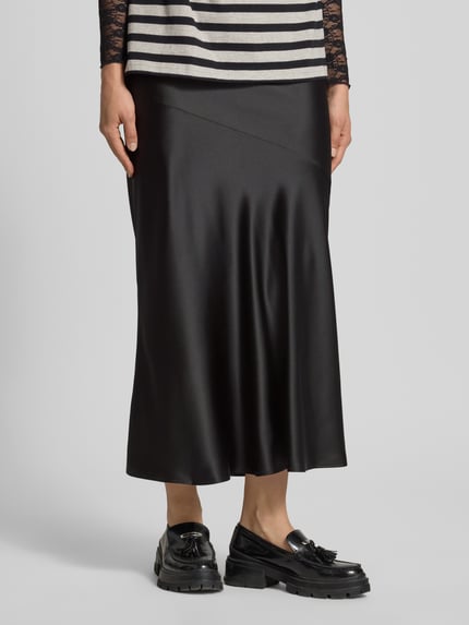 Frauenmodel trägt Satinrock mit elastischem Bund von Gina Tricot in Schwarz mit Gerader-Schnitt, Maxirock, Satin-Haptik, Nahaufnahme Unterkörper.