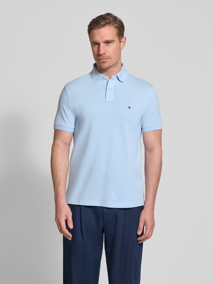 Męski model nosi Regular Fit Poloshirt aus Baumwoll-Mix od Tommy Hilfiger, efekt: jednolity kolor, krój regular fit, wyhaftowane logo, kołnierzyk polo, zapięcie na 2 guziki, krótki rękaw, wykończenie: z rozcięciem, wykończenie materiału: pika, mieszanka bawełny, całkowity widok z przodu.
