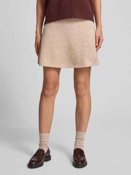 Frauenmodel trägt Strickrock mit elastischem Bund Modell 'Gisa' von Neo Noir, beigefarbener A-Linien-Minirock im Woll-Mix, Nahaufnahme Unterkörper.