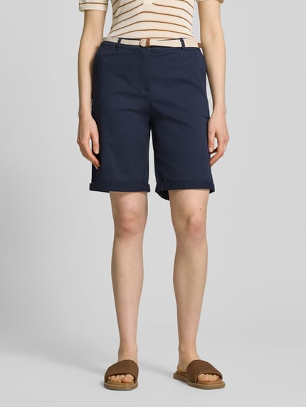 Modelka nosi Chino-Bermudas mit Gürtel von Christian Berg Woman z czystej bawełny, krój regular fit, pasek, szerokość w rozmiarze 36: 40 cm, długość nogawki od wewnątrz 23 cm, granatowy kolor, gładka tekstura, widok całej sylwetki z przodu.