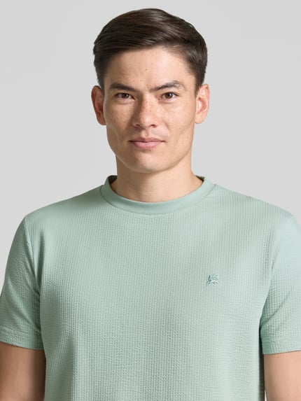 Mannelijk model draagt T-shirt met structuurmuster en logo-stitching van Lerros, katoenmix met stretch, regular fit, ronde hals, Nahaufnahme Oberkörper.