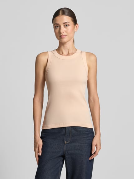 Kobiece modelka nosi Skinny Fit Tanktop aus reiner Baumwolle von DRYKORN w kolorze jasnobeżowym, efekt prążkowania, okrągły dekolt, długość tyłu 54 cm w rozmiarze S, widok całej sylwetki z przodu.