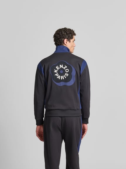 Männermodel trägt Regular Fit Sweatjacke mit Stehkragen van Kenzo, zwarte en blauwe kleuren, steekzakken met ritssluiting, elastische boorden, ruglengte 67 cm, schouderbreedte 51 cm, mouwlengte 61 cm, rugaanzicht, Ganzkörperansicht Rückansicht.