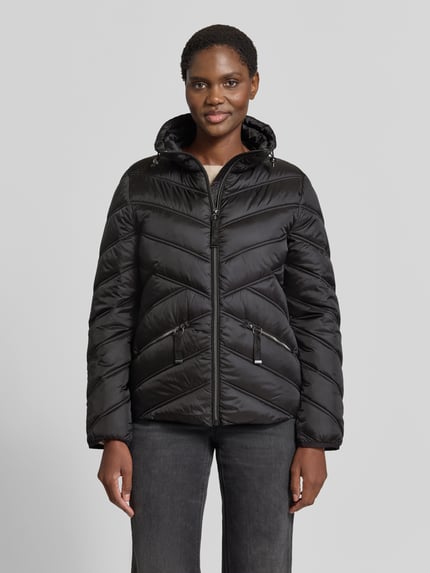 Frauenmodel trägt Steppjacke mit Stehkragen und Reißverschlusstaschen von Christian Berg Woman Selection in Schwarz, Ganzkörperansicht von vorne. Regular Fit, Reißverschluss, Reißverschlusstaschen, Rückenlänge 61 cm, Schulterbreite 42 cm, Brustweite 51 cm, Ärmellänge 58 cm.