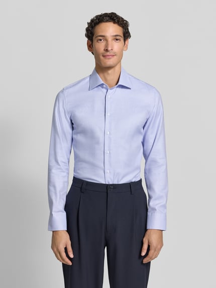 Mężczyzna nosi Slim Fit Businesshemd aus reiner Baumwolle von Seidensticker w jasnoniebieskim kolorze, gładka tekstura, Ganzkörperansicht von vorne.