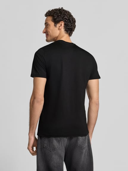 Męski model nosi Slim Fit T-Shirt mit Rundhalsausschnitt von GUESS, czarna bawełna, Wyhaftowane logo, długość tyłu 70 cm, Ganzkörperansicht Rückansicht