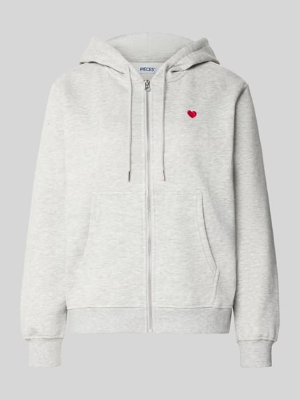 Produktfoto, hellgraue Relaxed Fit Sweatjacke aus Baumwoll-Mix Modell 'CHILLI' von PIECES mit Reißverschluss und rotem Herzdetail, glatte Oberfläche. Damen Sweatjacke