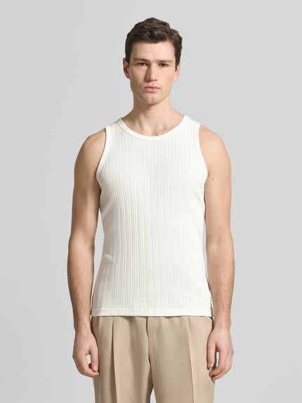 Männermodel trägt Tanktop mit Rundhalsausschnitt von Wood Wood aus Baumwoll-Mix in Weiß, Ripp-Optik, Slim Fit, Ganzkörperansicht von vorne.