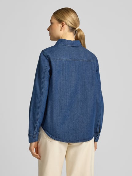 Frauenmodel trägt Regular Fit Jeanshemd aus Baumwoll-Lyocell-Mix Modell 'AURELAA' von Armedangels in Denim-Optik, Ganzkörperansicht Rückansicht.