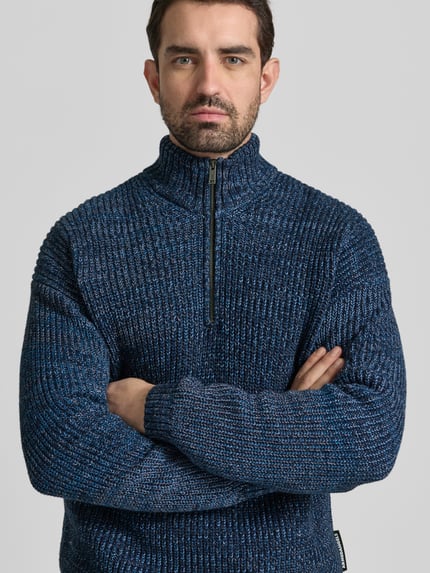 Männermodel draagt Relaxed Fit Troyer aus Baumwoll-Woll-Mix Modell 'MICHAAEL MOULINE' van Armedangels in melange blauw, grofgebreid, label patch, geribde boorden, korte ritssluiting, lange mouwen, Ganzkörperansicht van voren.