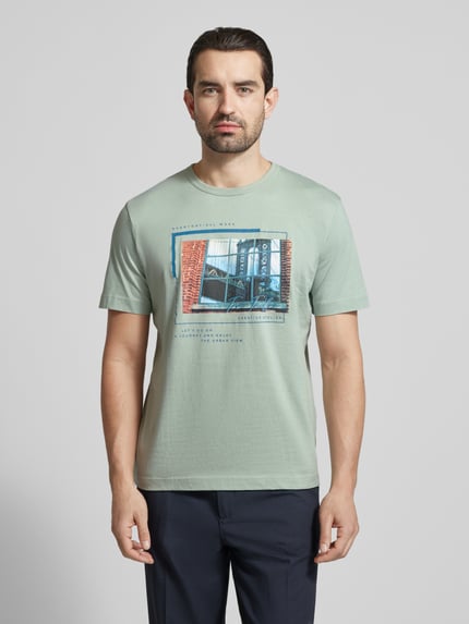 Męski model nosi Regular Fit T-Shirt aus reiner Baumwolle od Tom Tailor, gładka z foto-nadrukiem, okrągły dekolt, krój regular fit, jasna zieleń, krótki rękaw, jersey, widok całej sylwetki z przodu.