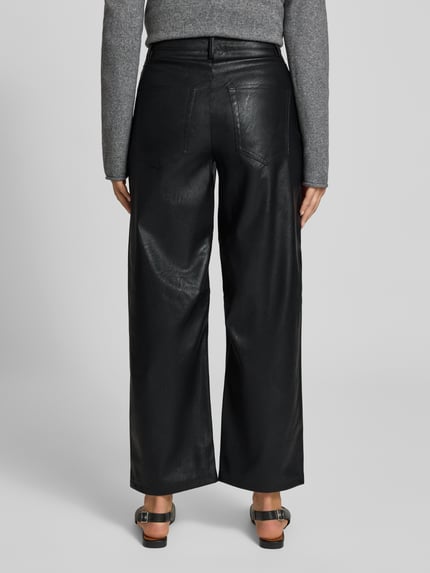 Frauenmodel trägt Wide Leg Hose mit Gürtelschlaufen Modell 'Talla' von Topshop aus schwarzem Lederimitat mit Eingrifftaschen, Ganzkörperansicht Rückansicht.
