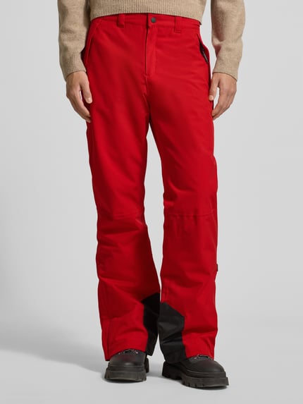 Männermodel trägt Flared Stoffhose mit Reißverschlusstaschen Modell 'KUMPULA' von LUHTA in kräftigem Rot, Knopf- und Reißverschluss, Ganzkörperansicht von vorne.
