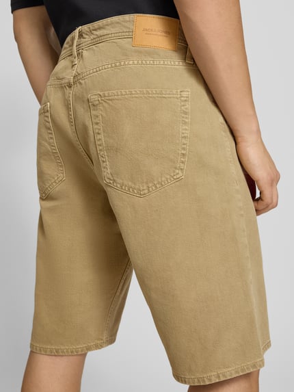 Männermodel trägt Baggy Fit Jeansshorts Modell 'ALEX' von Jack & Jones in Beige, reine Baumwolle, Eingrifftaschen, Ganzkörperansicht Rückansicht.