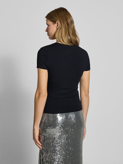Frauenmodel trägt Slim Fit T-Shirt mit Rundhalsausschnitt von Review aus elastischem Baumwoll-Mix, kurzärmelig, schwarze Farbe, Ganzkörperansicht Rückansicht.