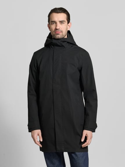 Männermodel trägt schwarzen Parka mit Ärmelriegeln Modell 'GEORGE' von Didriksons, Kapuze, Regular Fit, glatte Struktur, Ganzkörperansicht von vorne.