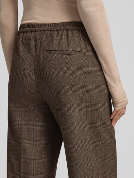 Frauenmodel trägt Jogginghose mit elastischem Tunnelzugbund von Marc O'Polo in unifarbener Optik mit Bundfalte und elastischem Bund, Nahaufnahme Rückansicht.