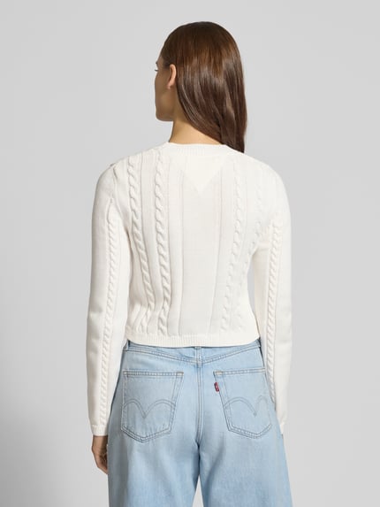 Frauenmodel trägt Slim Fit Strickpullover aus reiner Baumwolle von Tommy Jeans, Optik: Unifarben, Strickoptik, Ganzkörperansicht Rückansicht.
