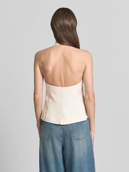 Frauenmodel trägt Weste aus Leinen mit Pattentaschen Modell 'BORELI' von Mango, cremefarben, glatte Textur, Ganzkörperansicht Rückansicht, Slim Fit, Knopfleiste, reine Leinenqualität, Rückenlänge 26 cm, Schulterbreite 30 cm, Brustweite 34 cm.