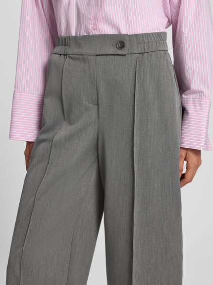 Frauenmodel trägt Stoffhose mit Bügelfalte Modell 'Cisilia' von someday, grauer Material-Mix, Barrel Fit, Nahaufnahme Oberkörper.
