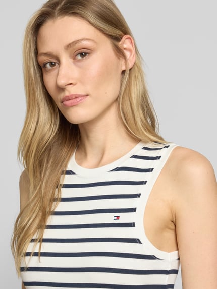 Frauenmodel trägt Slim Fit Tank Top aus reiner Baumwolle Modell 'SLIM CODY' von Tommy Hilfiger in Optik: Unifarben, Allover-Muster, Logo-Stitching, Rundhalsausschnitt, Trägerform: breite Träger, Material: reine Baumwolle; Nahaufnahme Oberkörper.