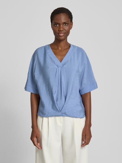 Frauenmodel trägt Blusenshirt mit V-Ausschnitt von Christian Berg Woman in Hellblau, strukturierte Oberfläche, Regular Fit, Halbarm, Ganzkörperansicht von vorne.