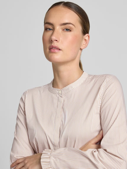 Kobiece model prezentuje bluzkę z mieszanki bawełny z dodatkiem streczu MOS MOSH Bluse mit Mao-Kragen und Rüschenärmeln Modell 'Mattie', proste paski, stójka, zakryta listwa guzikowa, rękawy z falbanami, długość tyłu w rozmiarze S: 65 cm, długość rękawów w rozmiarze S: 62 cm, krój straight fit, zbliżenie na górną część sylwetki z przodu.