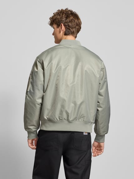 Mężczyzna model nosi Bomberjacke mit Label-Stitching od Calvin Klein Jeans, regular fit, srebrzysty kolor, widok całej sylwetki z tyłu.
