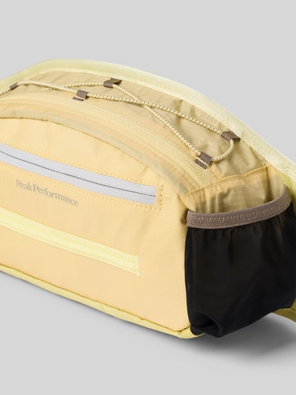 Produktfoto, Trail Hip Bag mit Logo-Print und Reißverschlussfach von Peak Performance in geel, ritsvak vooraan, verstelbare kliksluiting, dames tas, hoofdvak met ritssluiting, breedte 32 cm, lengte 17 cm, diepte 9 cm, schouderbandlengte 67 cm