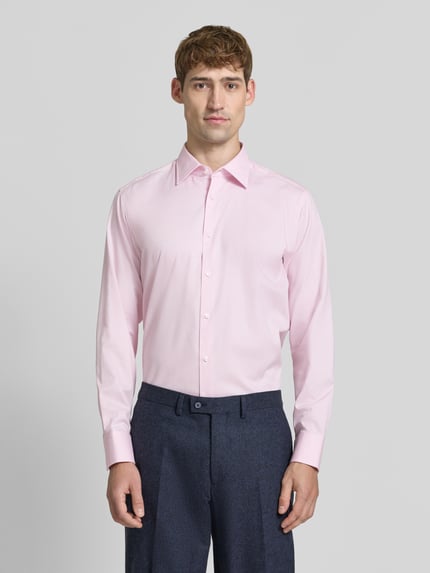 Männermodel trägt Regular Fit Businesshemd mit Kentkragen Modell 'H-JOE-K' von BOSS, unifarben, langarm, Knopfleiste, Ganzkörperansicht von vorne.