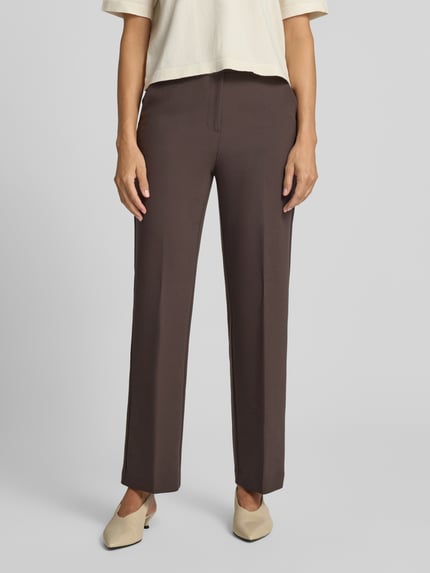 Frauenmodel trägt Straight Fit Hose mit Viskose-Anteil von COMMA, braun, elastischer Stoff, Bügelfalten, Nahaufnahme Unterkörper, Ganzkörperansicht von vorne.